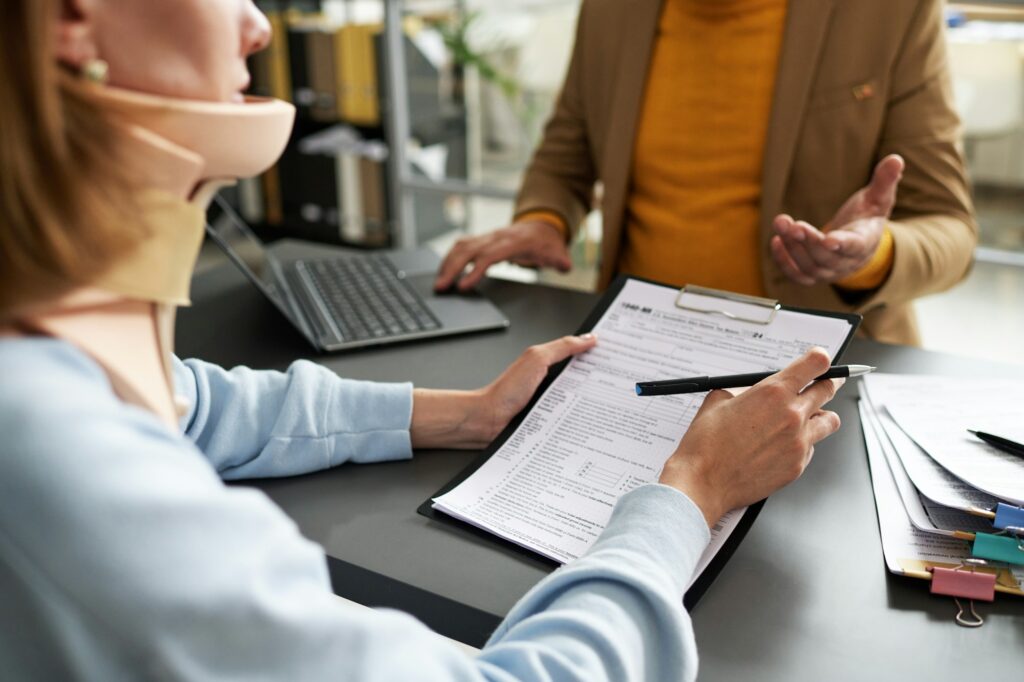 Woman with injury signing contract with insurance agent